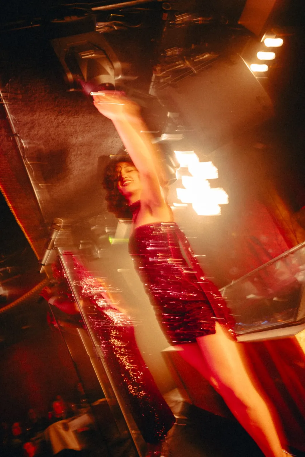 Performer in a red sequin dress lit by stage lights at the Dinner Show