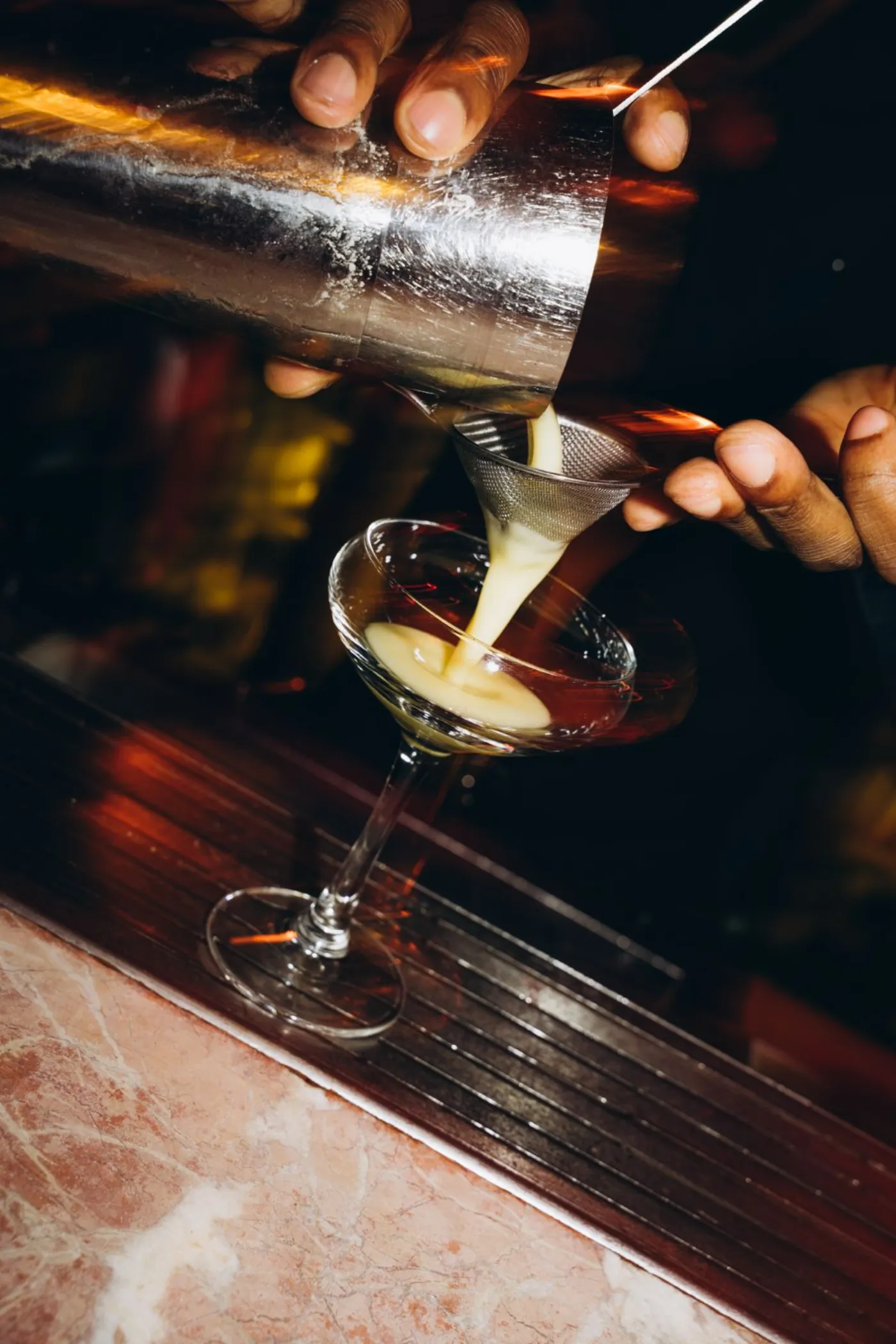 Cocktail wordt aan de bar in een coupe geschonken